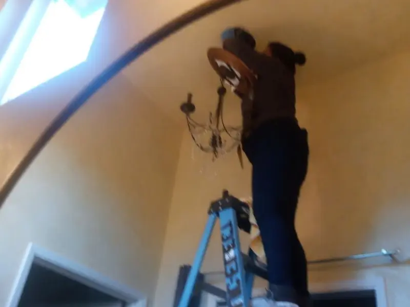 Electrician installing a chandelier in a McLendon-Chisholm residence